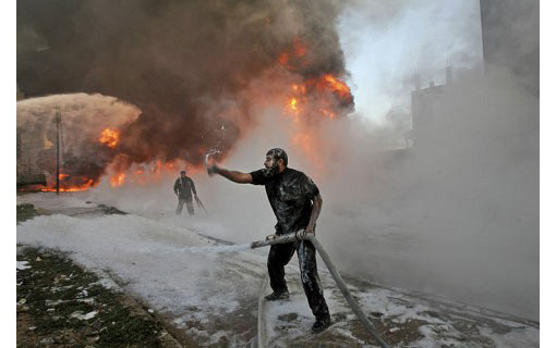 Palestinian firefighters try to put out flames in a refuge camp building