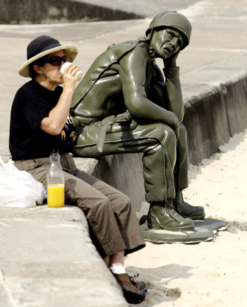 a visitor to Sydney’s Tamarama Beach enjoys a refreshment near a sculpture titled Soldier Scale 1:1