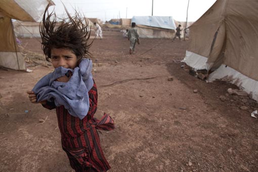 a girl stands next to her tent as wind and rain pass through the tent city at Jalozai camp on June 2, 2009, 15km from Peshawar, Pakistan