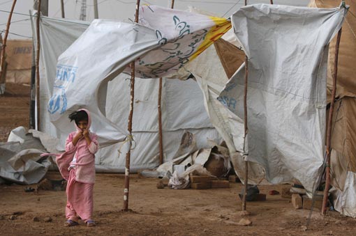 a girl stands next to her tent as wind and rain pound the massive tent city June 2, 2009 at Jalozai camp, 15km from Peshawar, Pakistan