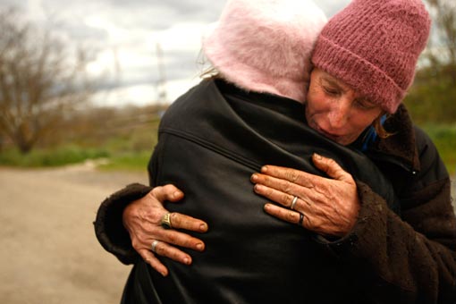 Jackie Dickens, right, receives a hug of support from Renee Hadley. Both of them have been living in tent city for the last year