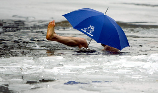  A member of the 'Seehunde Berlin' winter and ice swimming club, swims with an umbrella in the frozen Oranke Lake in Berlin, Friday, Dec. 25, 2009. It is an annual event that club members meet for a Christmas swim at the lake.