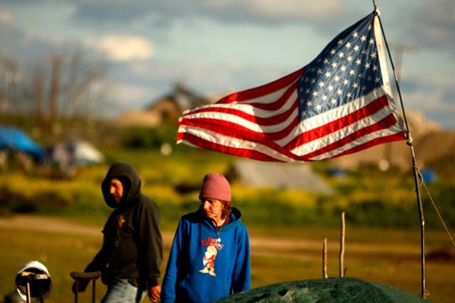 Jackie Dickens stands next to her tent, which flies the American flag. Sacramento city officials who had more or less ignored the camp announced Thursday that they plan to shut it down within a month