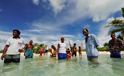 Villagers on the island of Abaiang (a tiny village on an outer island of the Pacific republic of Kiribati) stand in the sea where their homes used to be. Over the past 40 years the villagers have seen the sea rise, storm surges become more frequent and spring tides more forceful.