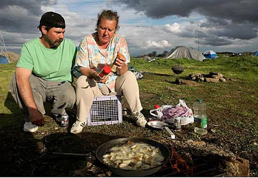 Newly homeless couple Tammy Day (R) and her husband Keith Day wait for their dinner to cook at a homeless tent city March 4, 2009 in Sacramento, California. The tent city is seeing an increase in population as the economy worsens and more people are becoming unemployed and having their homes slip into foreclosure