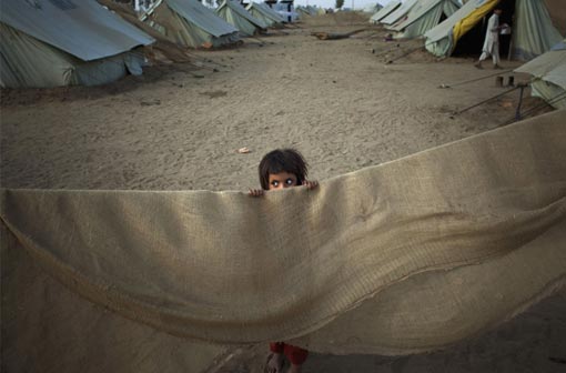 a Pakistani girl peers over part of a makeshift tent in Chota Lahore Refugee Camp in Swabi, Pakistan on Wednesday, May 20, 2009