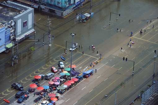 people wading through floodwaters on the main road of the ancient Thai capital of Ayutthaya, north of Bangkok, on October 11