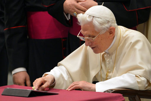 Pope Benedict XVI clicks on a tablet to send his first twitter message at the Paul VI hall at the Vatican, December 12, 2012