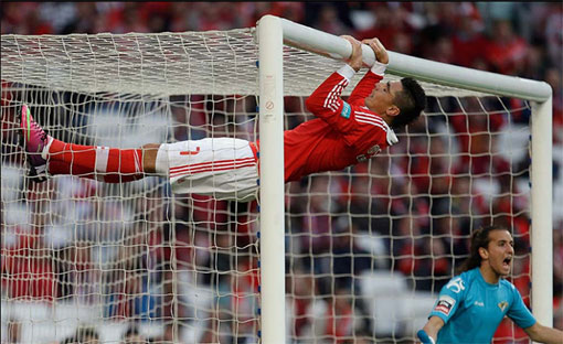 soccer player hangs on to the goal bar after missing chance to score